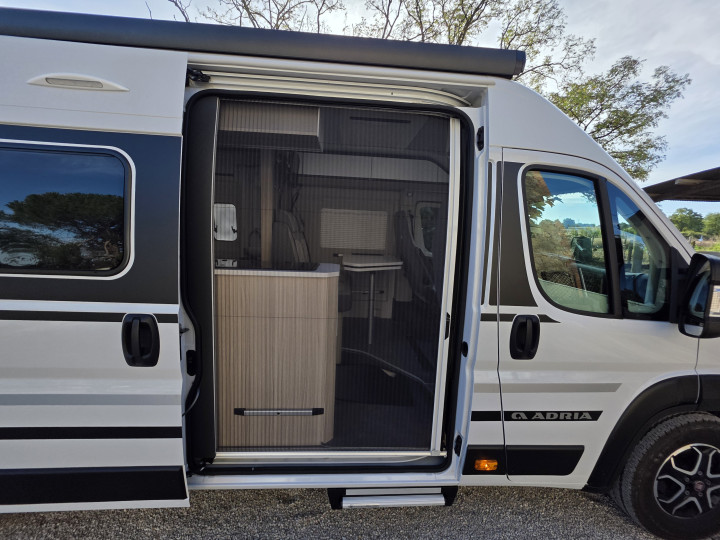Vue latérale de l’Adria Twin Plus avec porte coulissante ouverte