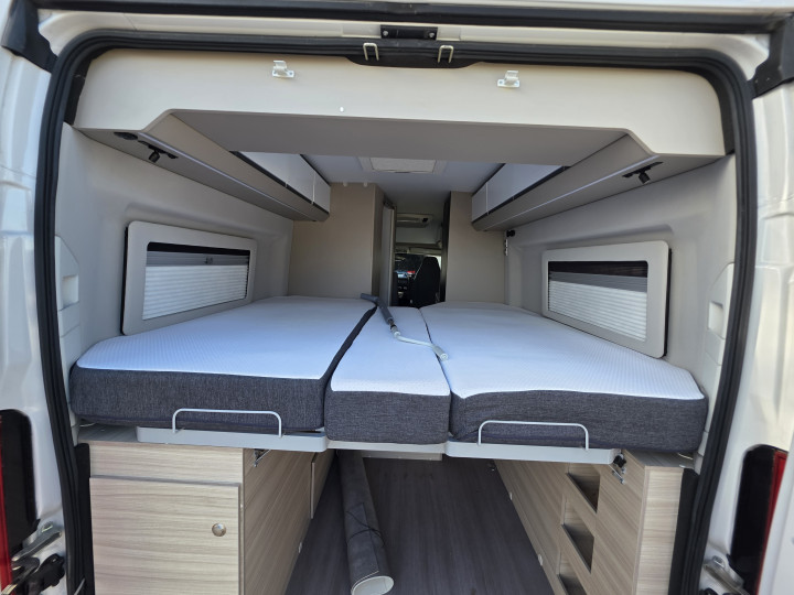 Lits relevés pour accéder au volume de rangement arrière de l’Adria